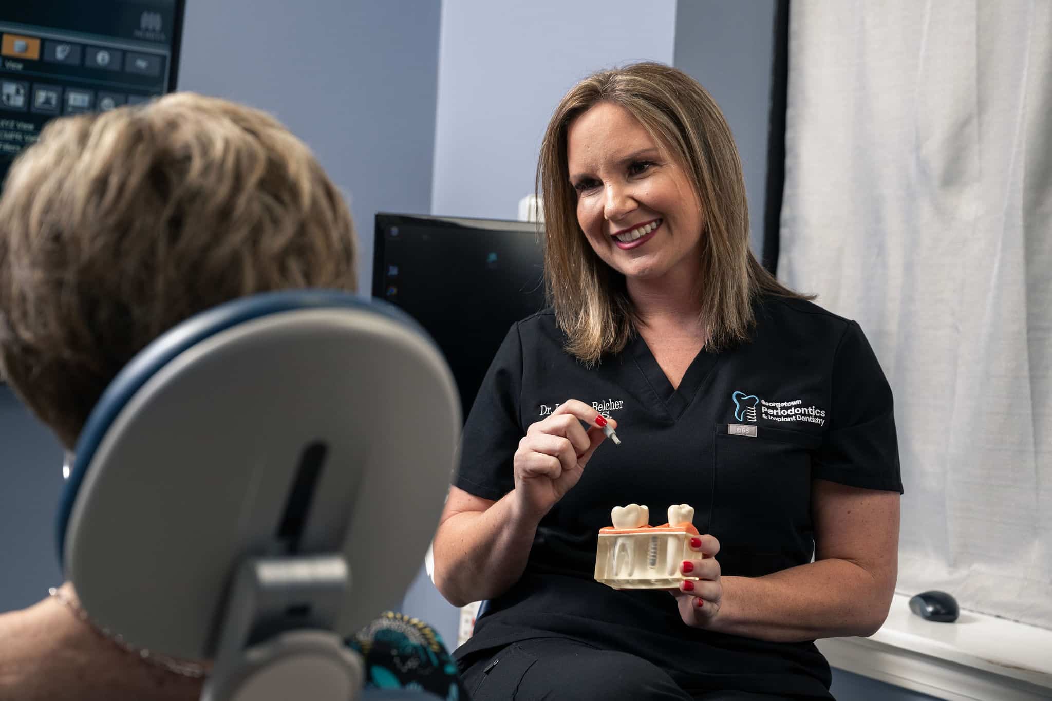 Dr. Lucy Belcher walking a patient through a dental implant model at Georgetown Periodontics